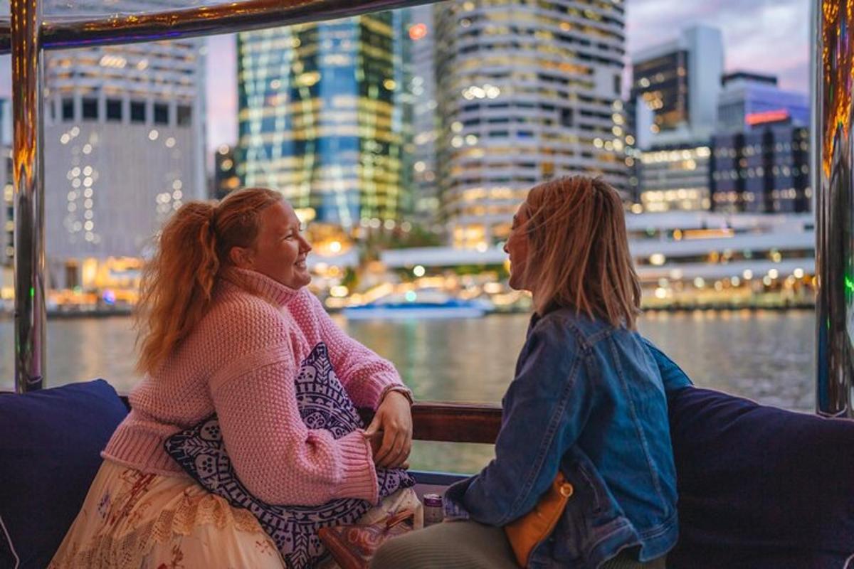 two women sitting on a boat looking at a city