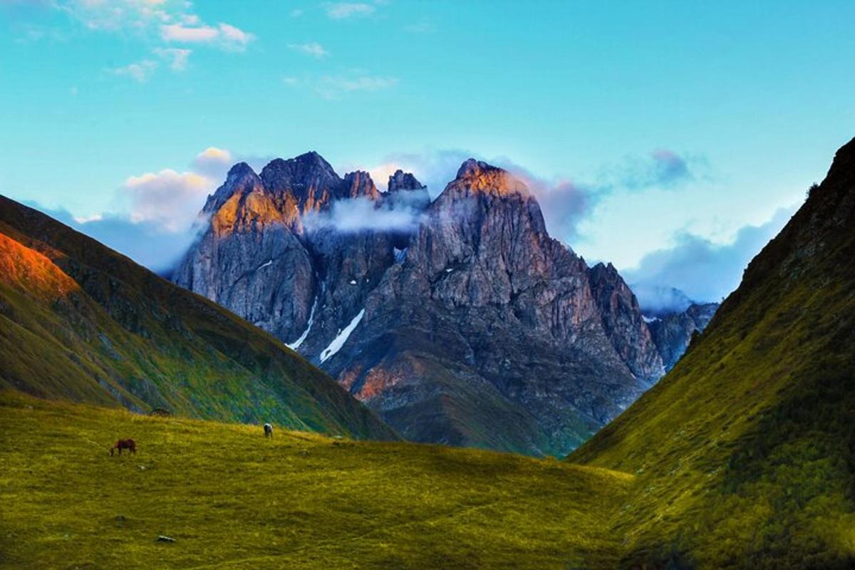 una vista di una catena montuosa con un campo verde
