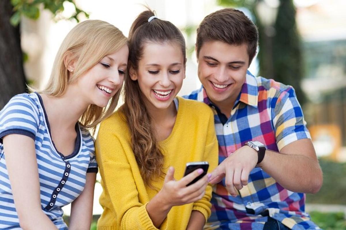 a group of three people looking at a cell phone