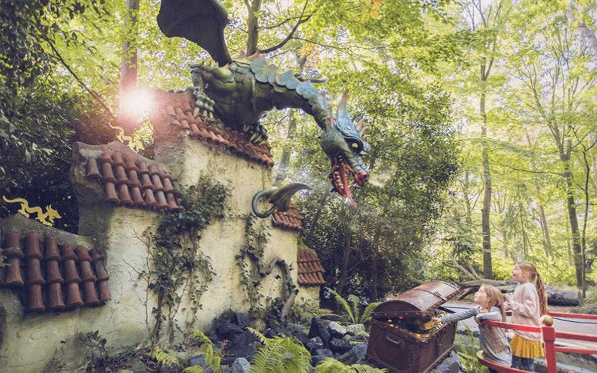 two children standing next to a building with a dragon head