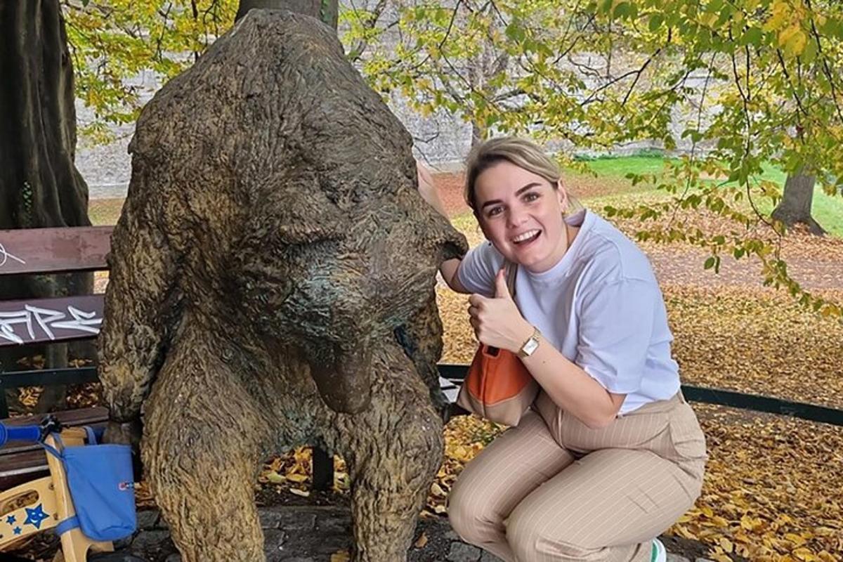 una donna inginocchiata accanto alla statua di un orso