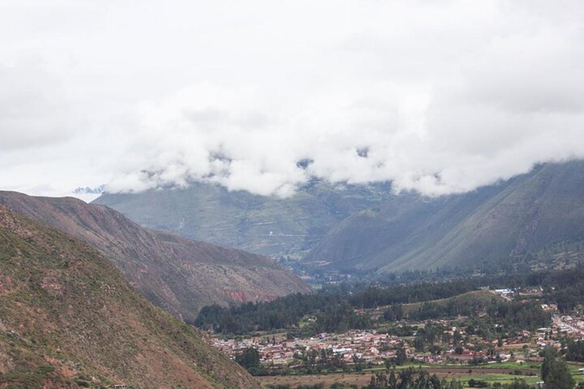 una vista d'una vall de muntanya amb una ciutat i núvols