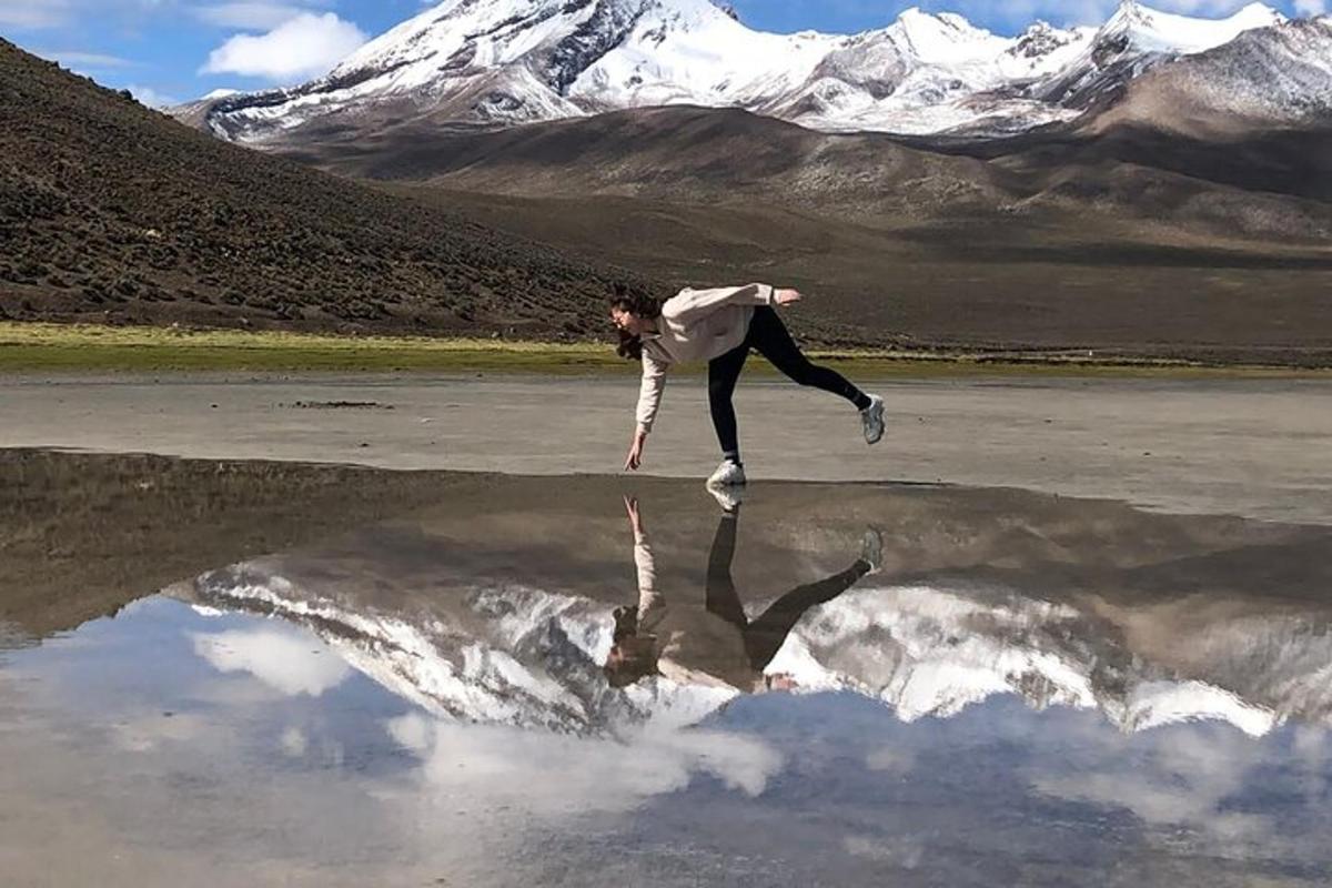 Un hombre está saltando al agua frente a una montaña.