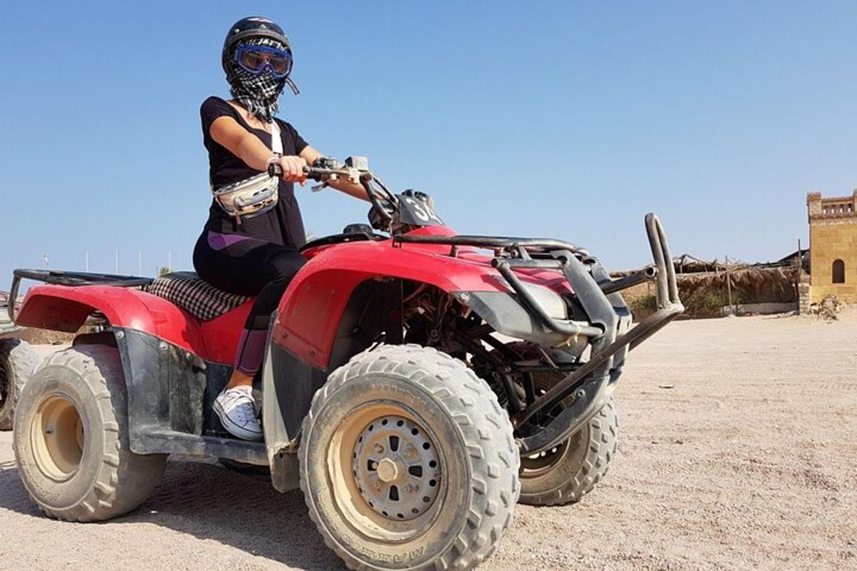 een persoon die achterop een rode ATV zit