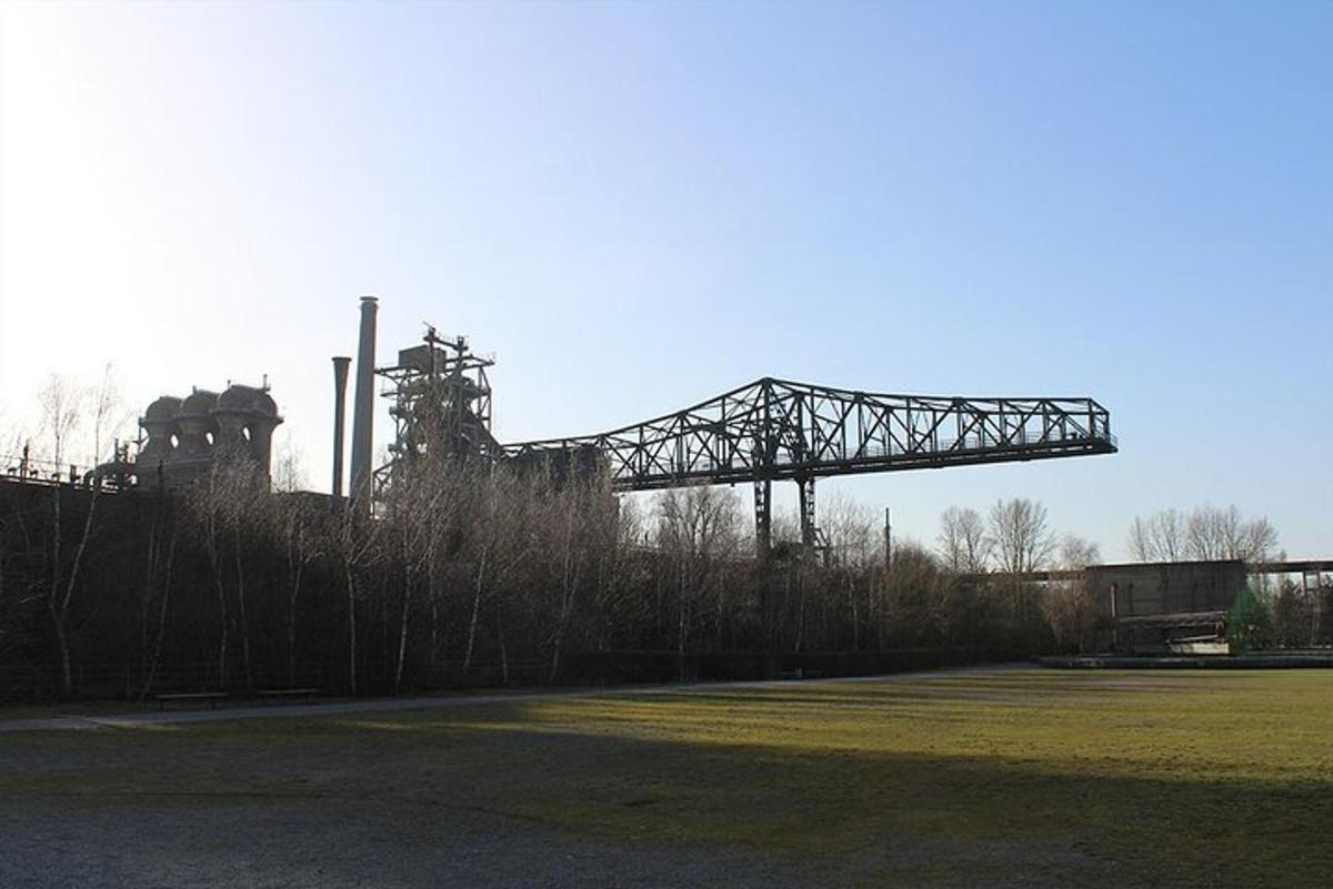 uma ponte de metal sobre um campo com um edifício ao fundo