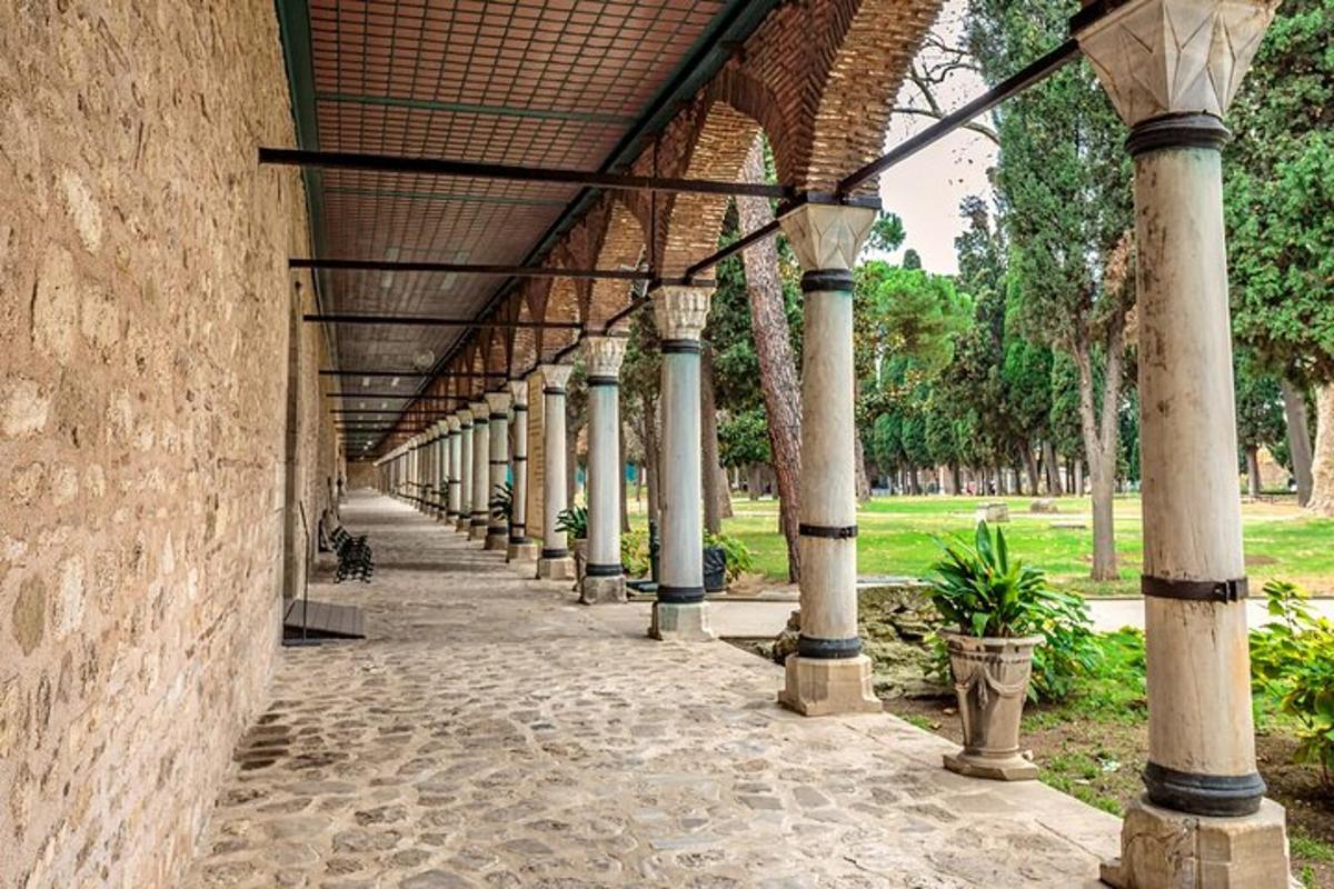 Un edificio con columnas y una pasarela en un parque.