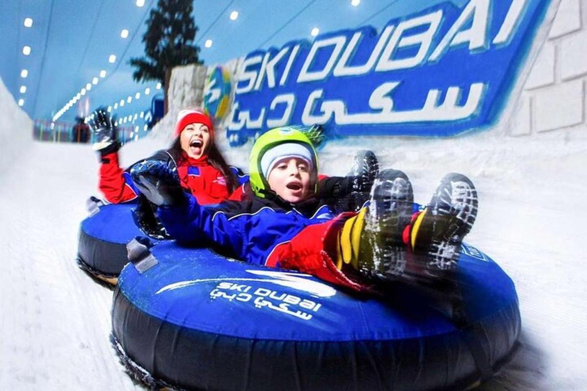 two people are riding on an inner tube in the snow