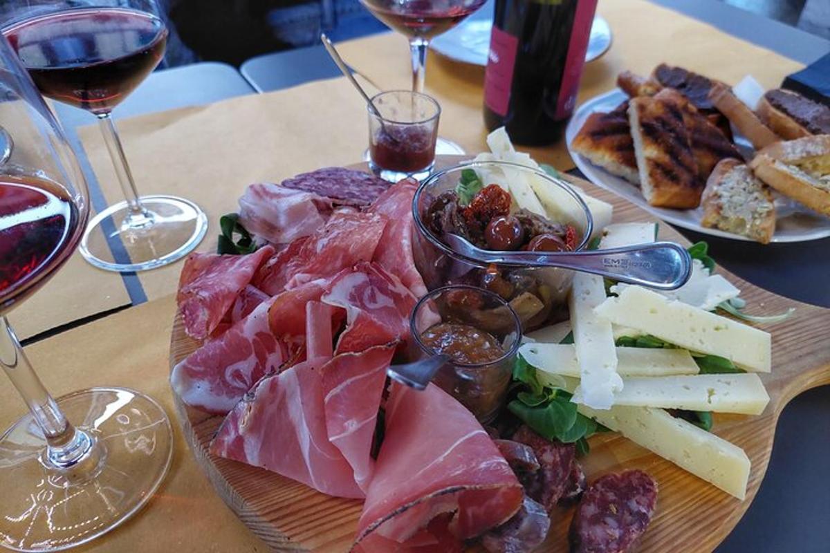 a plate of meat and cheese and glasses of wine