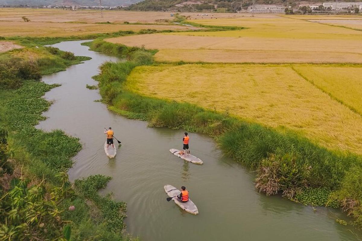 tiga orang berkayak di sungai dengan rumput