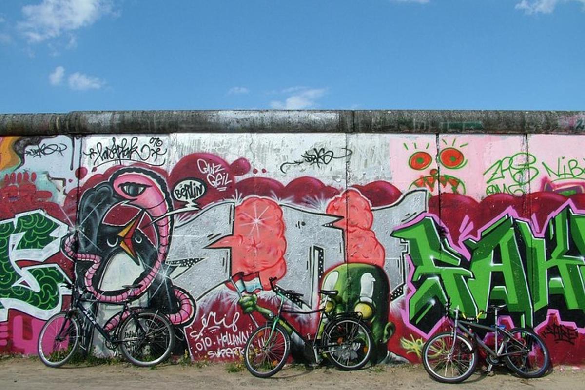 tre sykler parkert foran en vegg med graffiti