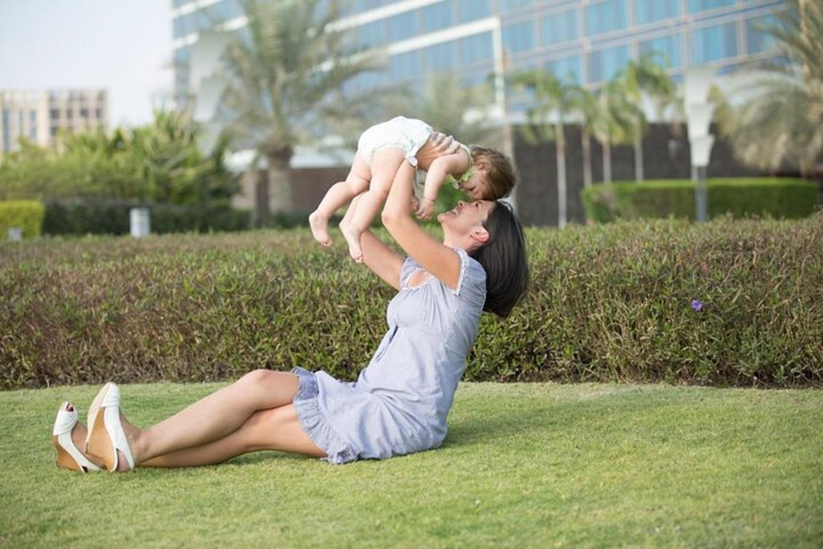 en kvinde sidder på græsset og holder en baby
