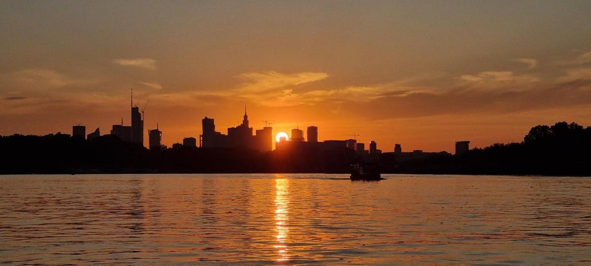 a city skyline with the sun setting over a body of water