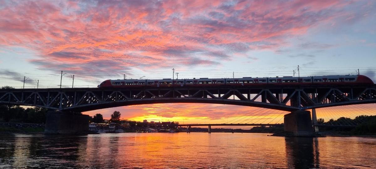 a train on a bridge over a river at sunset