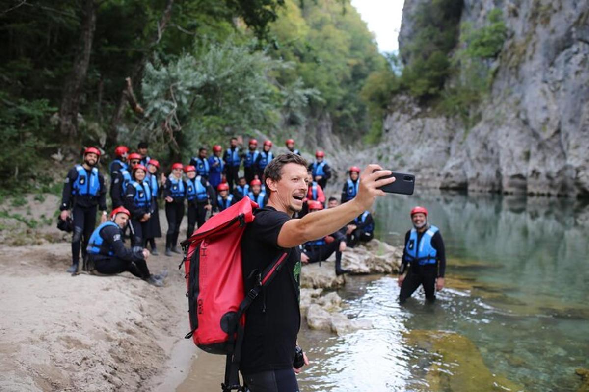 muž fotografující skupinu lidí v řece