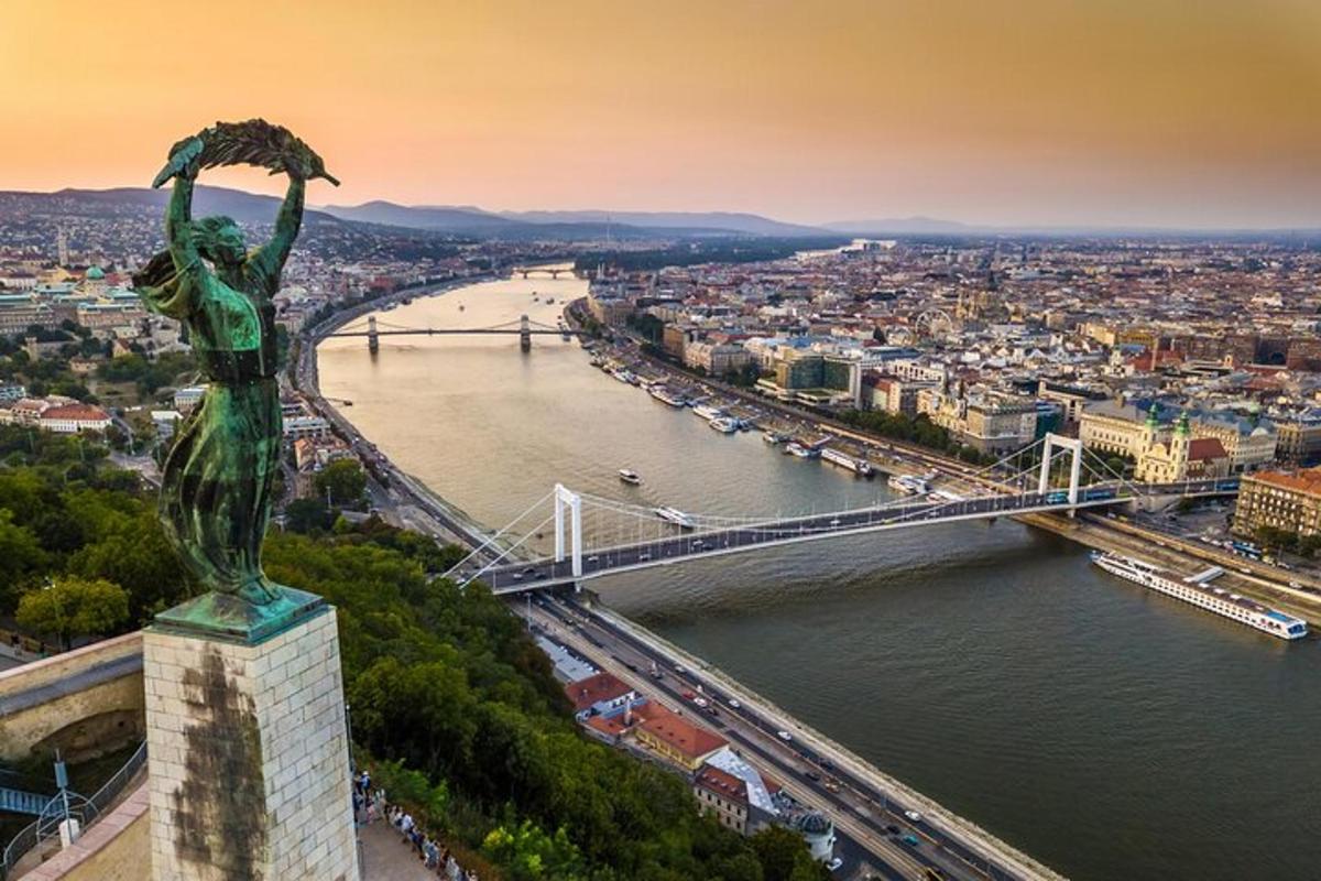 a statue of a woman with her arms in the air next to a bridge