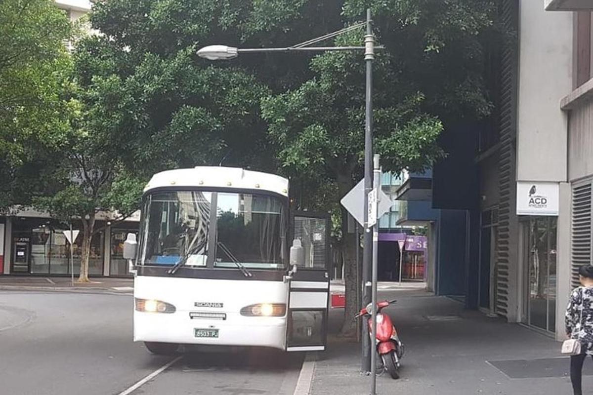 en hvit buss parkert ved siden av en moped på en gate