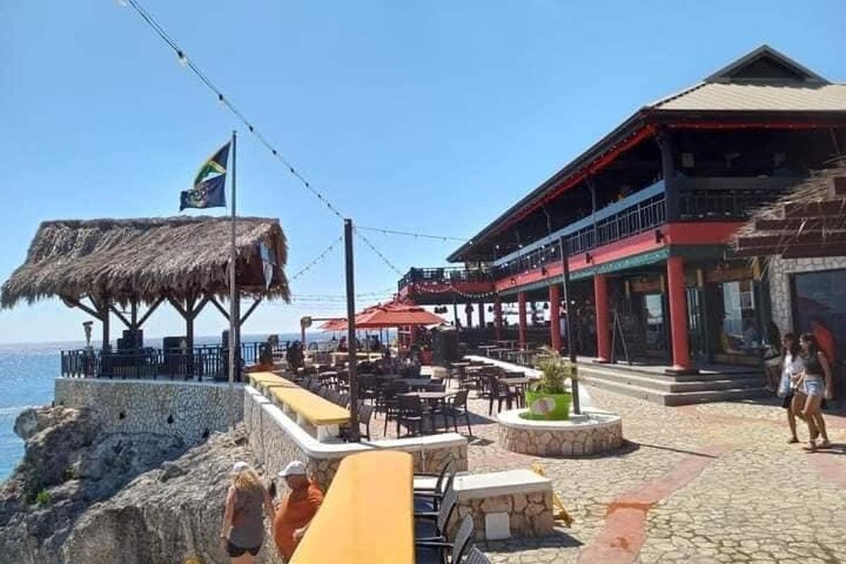 um restaurante com mesas e cadeiras e o oceano