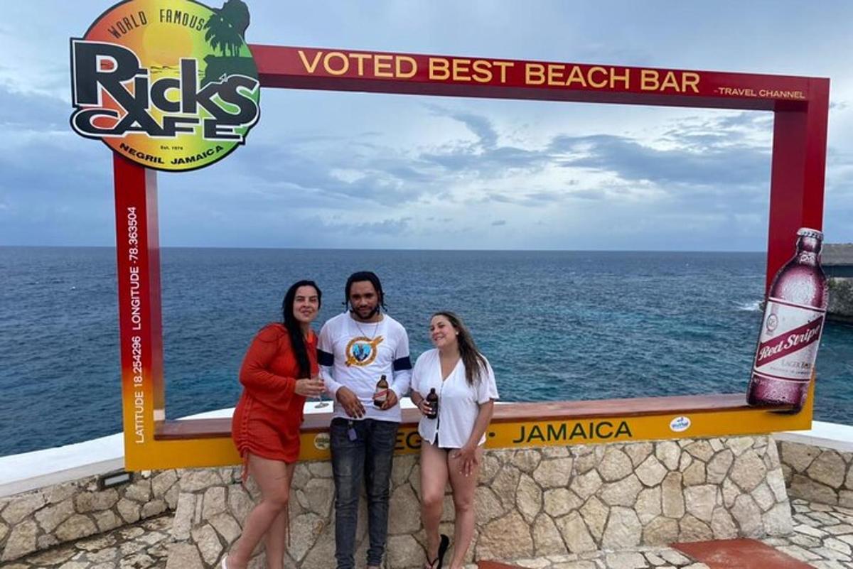 a group of three people standing next to the ocean