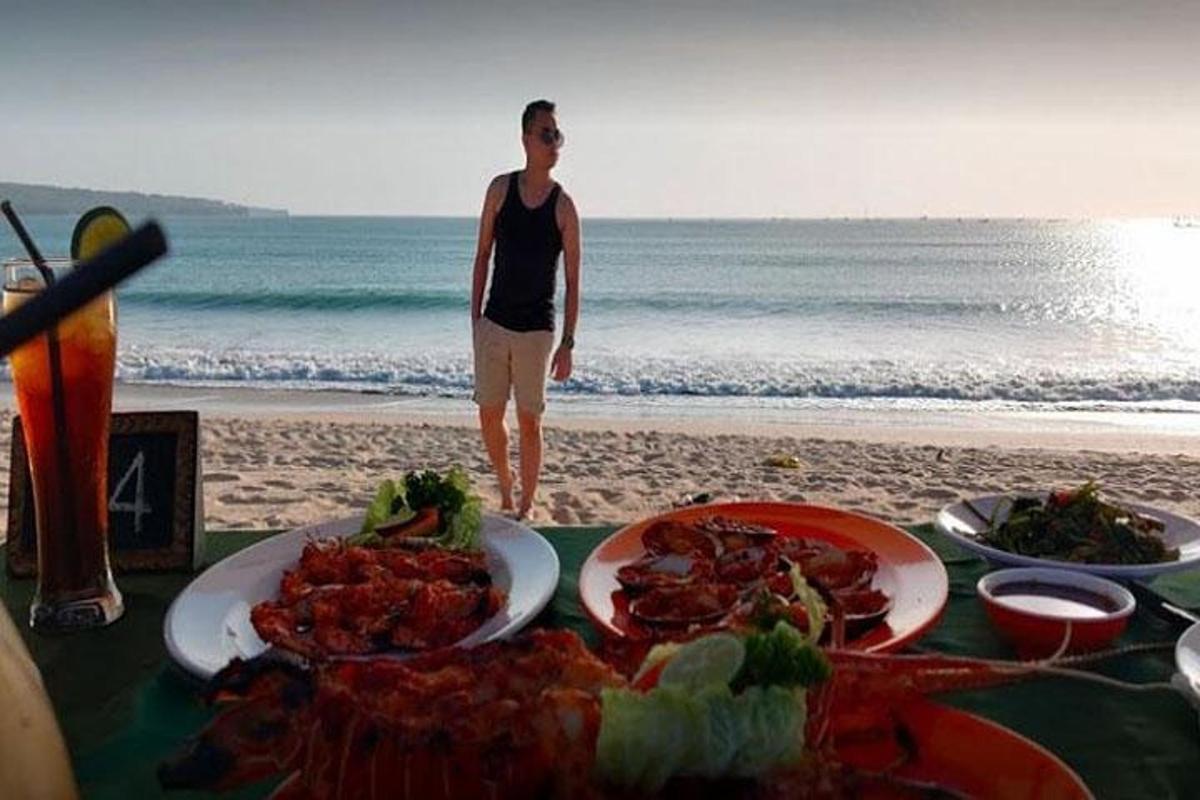 um homem em pé na praia com uma mesa de comida