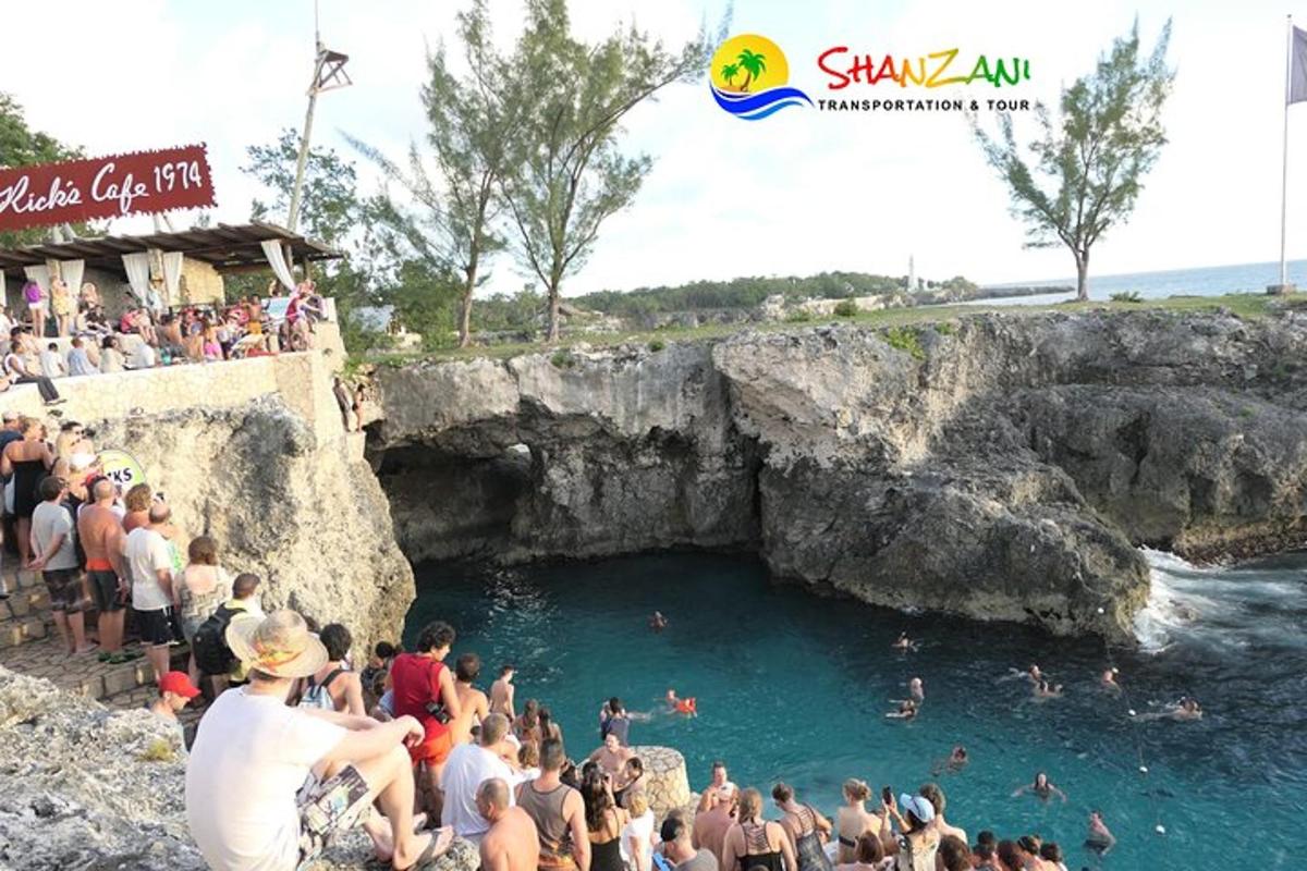 a crowd of people standing around a cave in the water