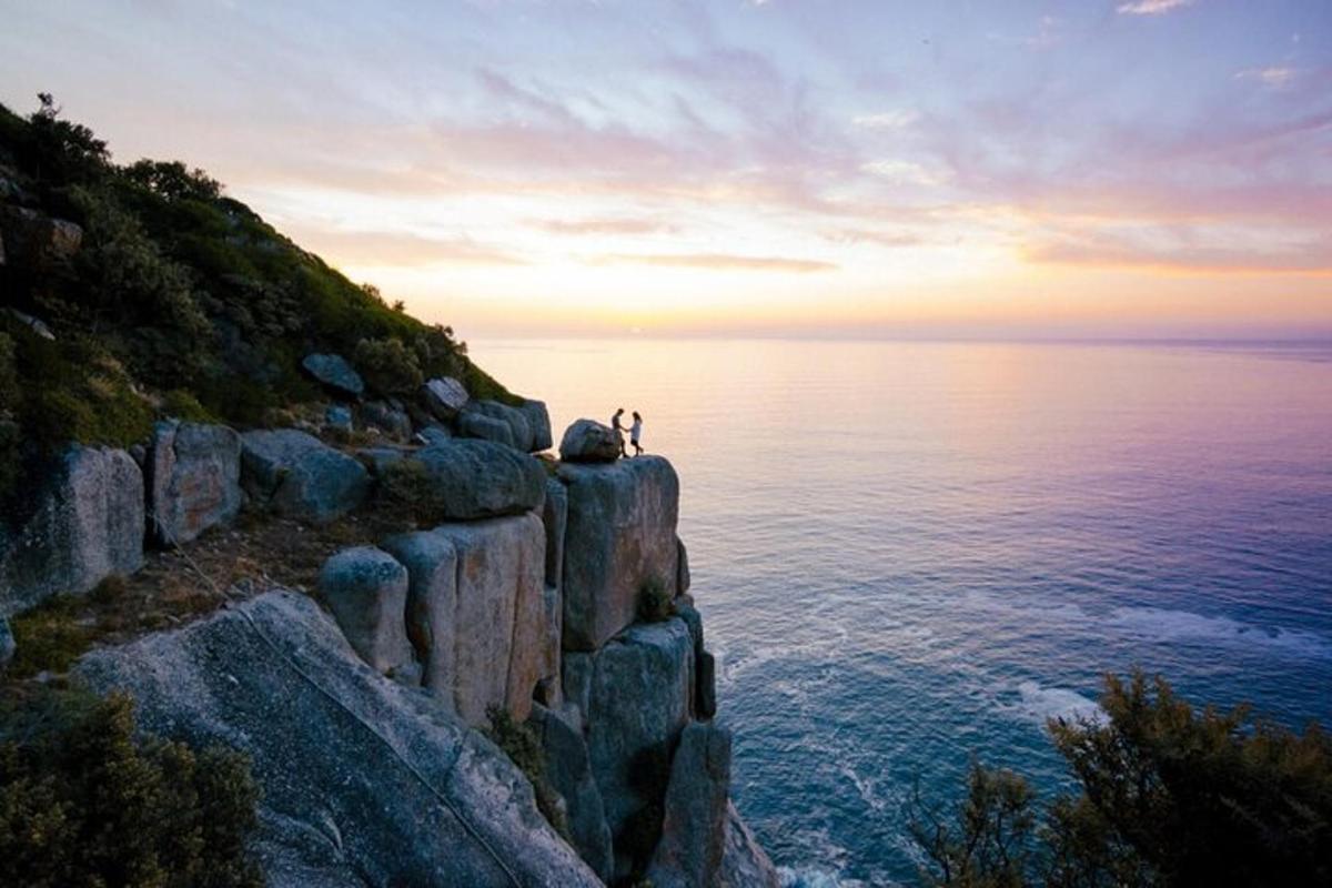 a person sitting on a cliff overlooking the ocean