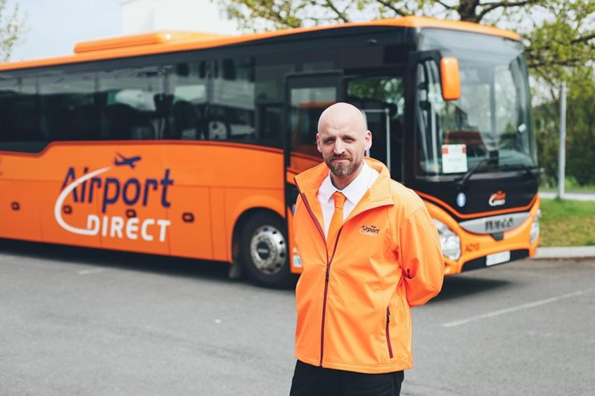 muž v oranžovém pláštěnce stojící před autobusem