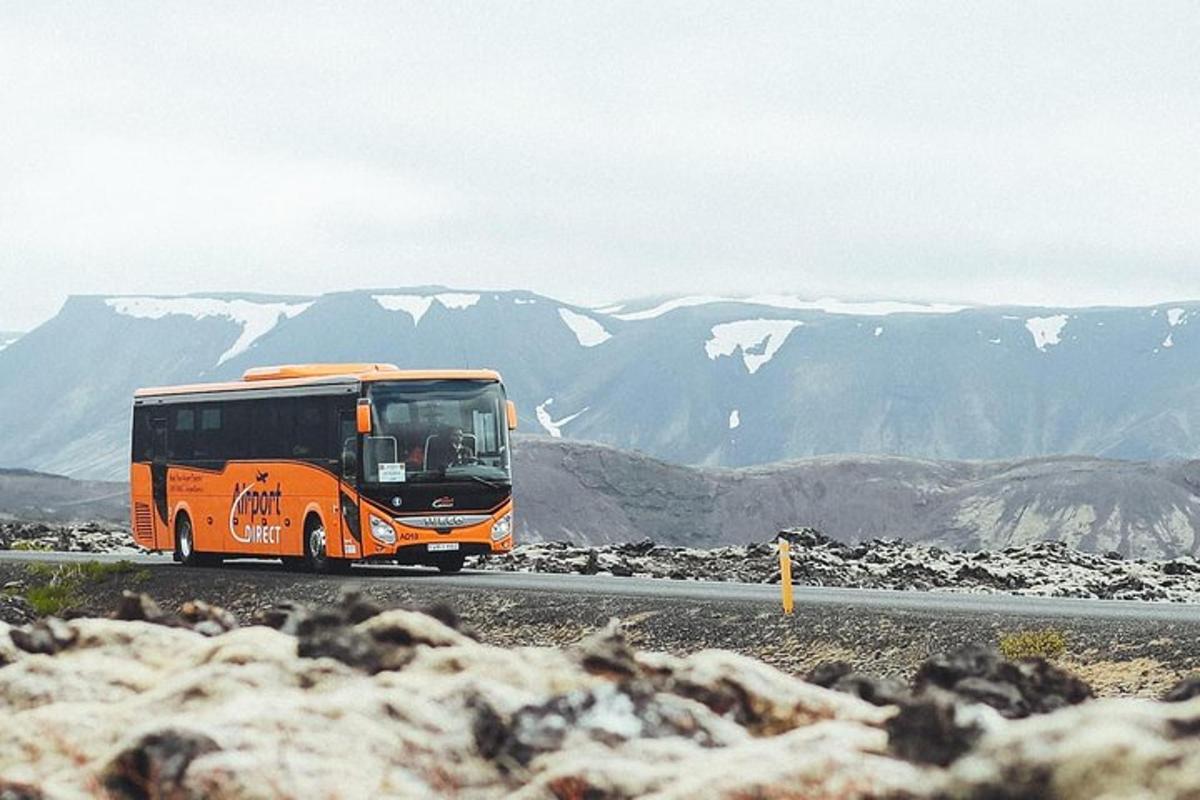 oranžový autobus jedoucí po silnici s horami v pozadí