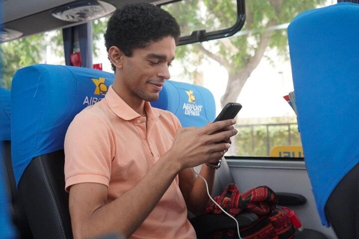 muž sedící v autobuse a dívající se do svého mobilního telefonu