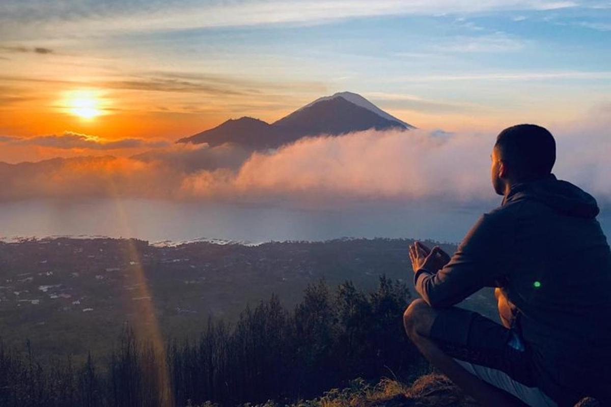 seorang lelaki duduk di atas gunung pada waktu matahari terbenam