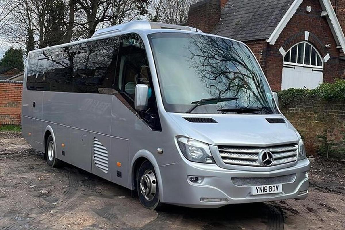 stříbrný autobus zaparkovaný před domem