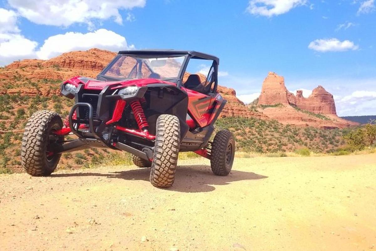 sebuah atv merah dan hitam diletakkan di padang pasir