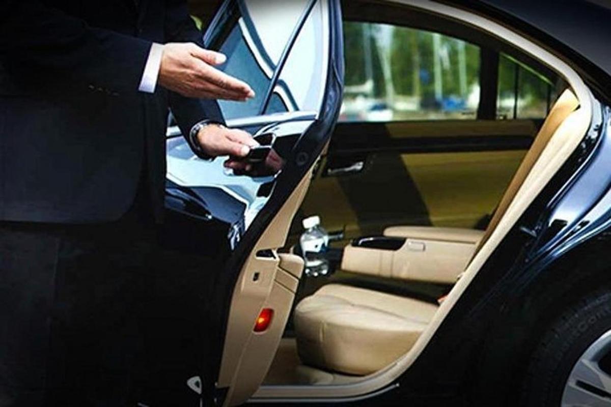 a man holding a cell phone in the door of a car