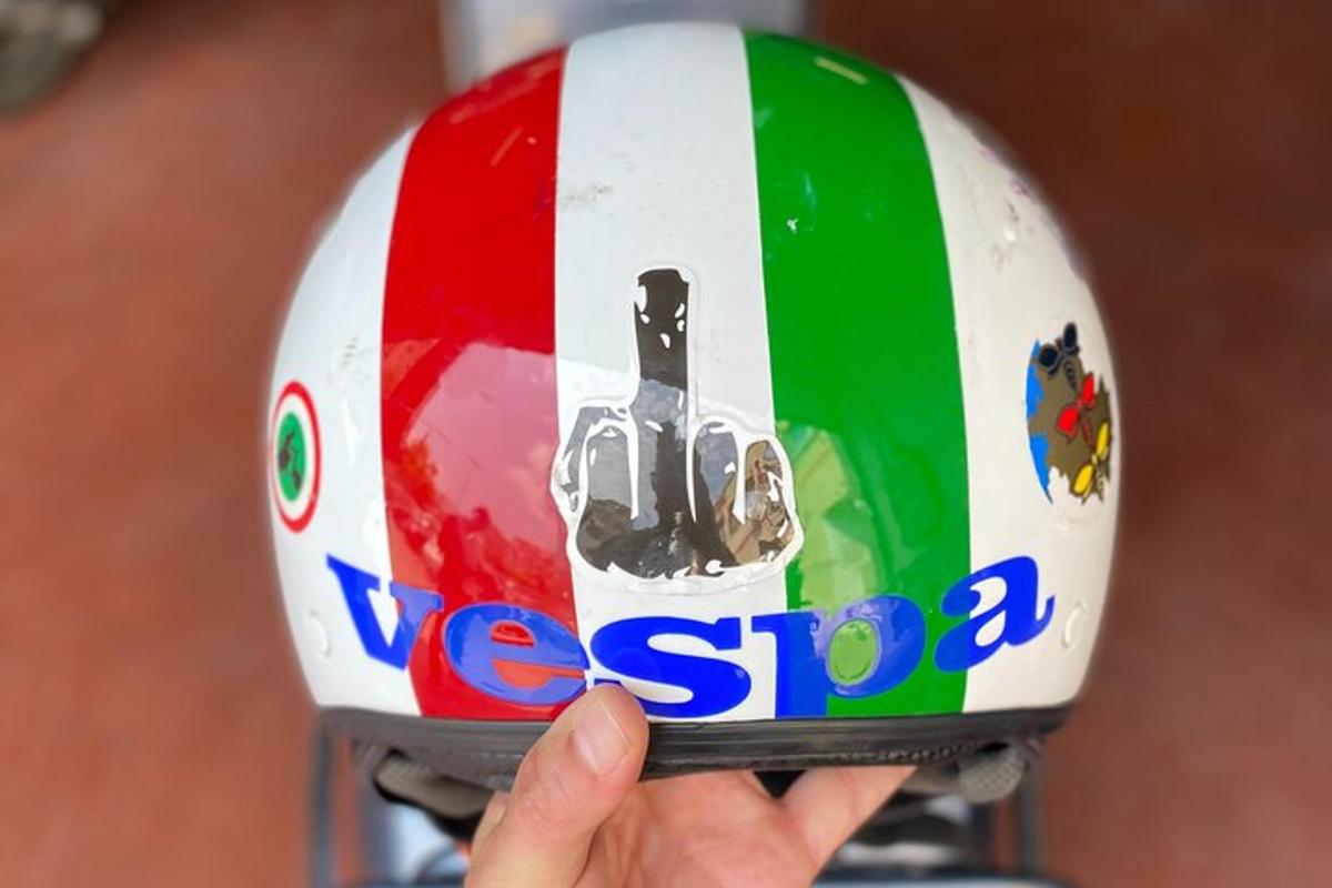 Maður heldur á hjálmi og áletrunin „vespa“ stendur