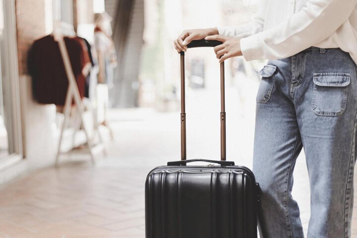 a woman is holding a black suitcase