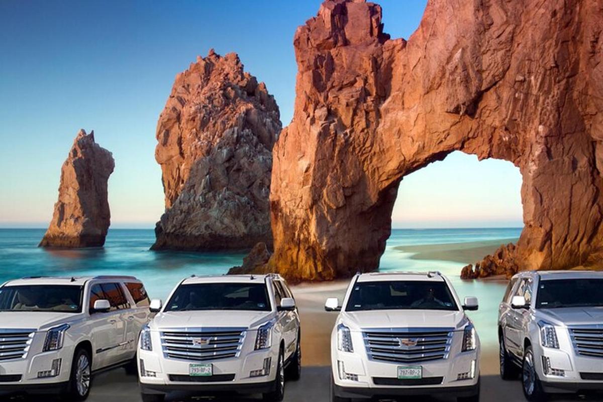 Un grupo de coches aparcados frente a una formación rocosa.