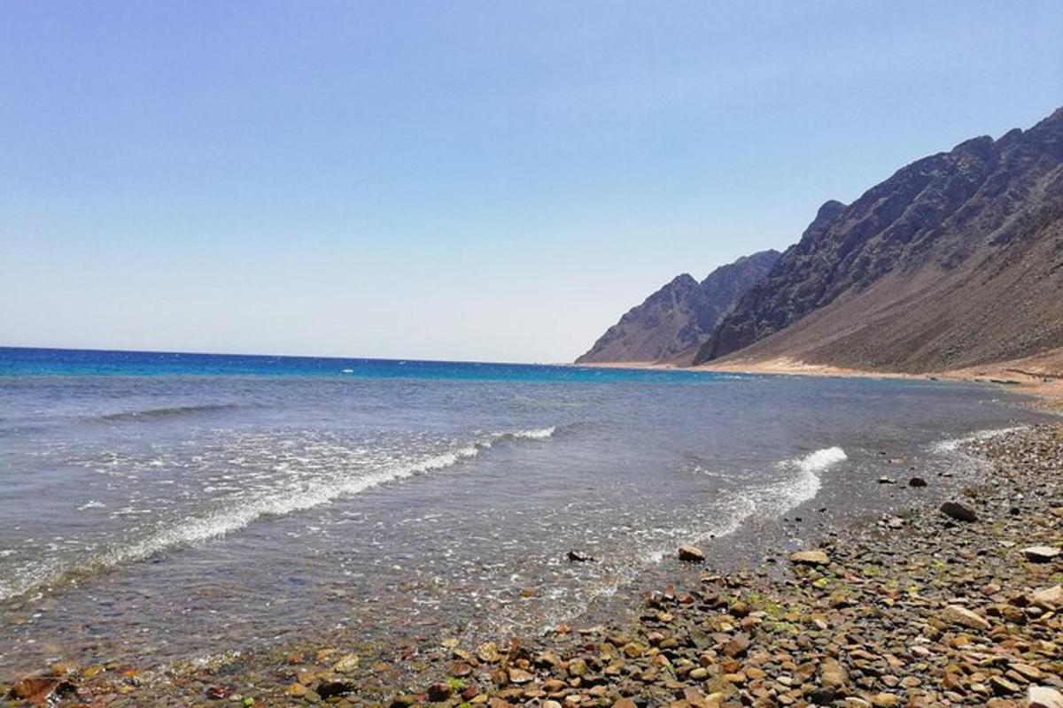 pantai dengan latar belakang lautan dan gunung