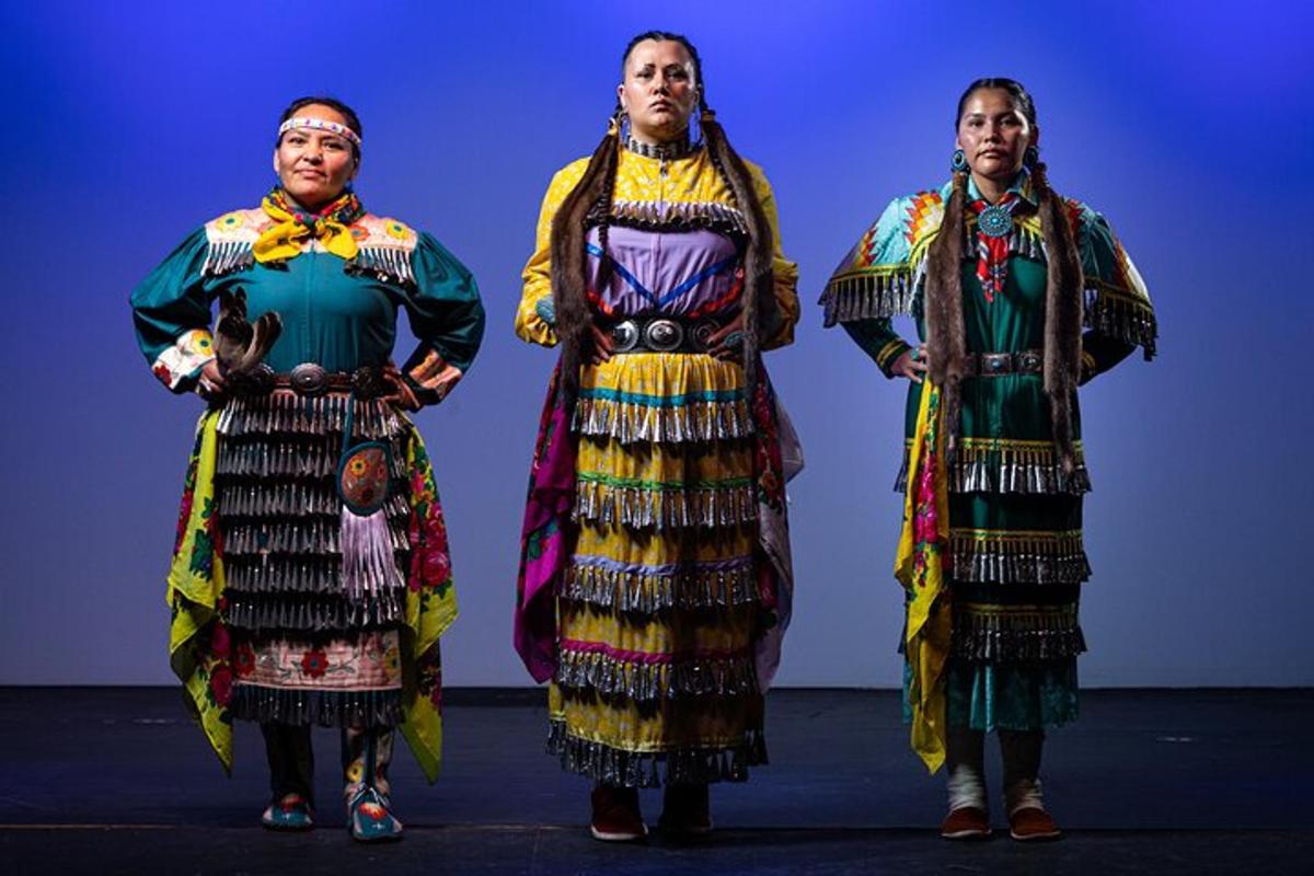 a group of three women in traditional clothing on a stage