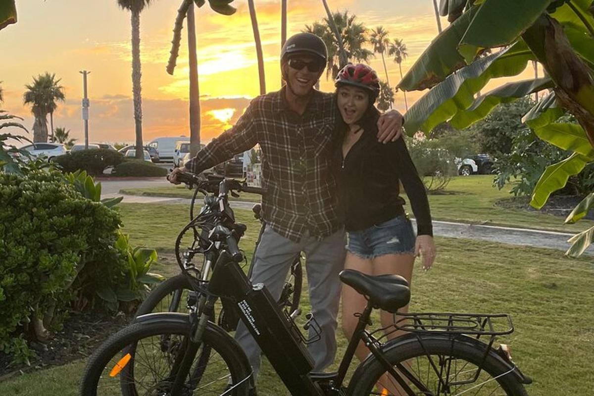um homem e uma mulher parados ao lado de uma bicicleta