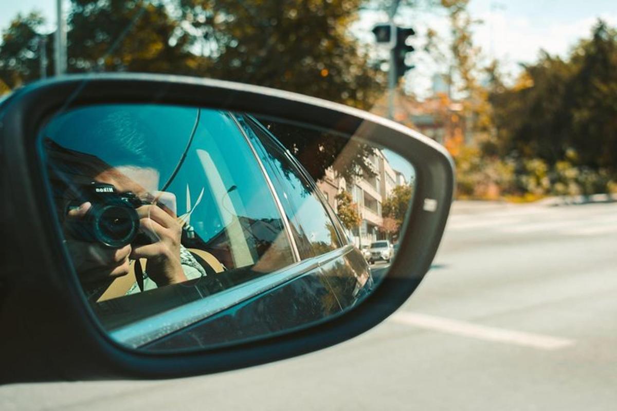 ženska, ki fotografira avtomobil v stranskem ogledalu