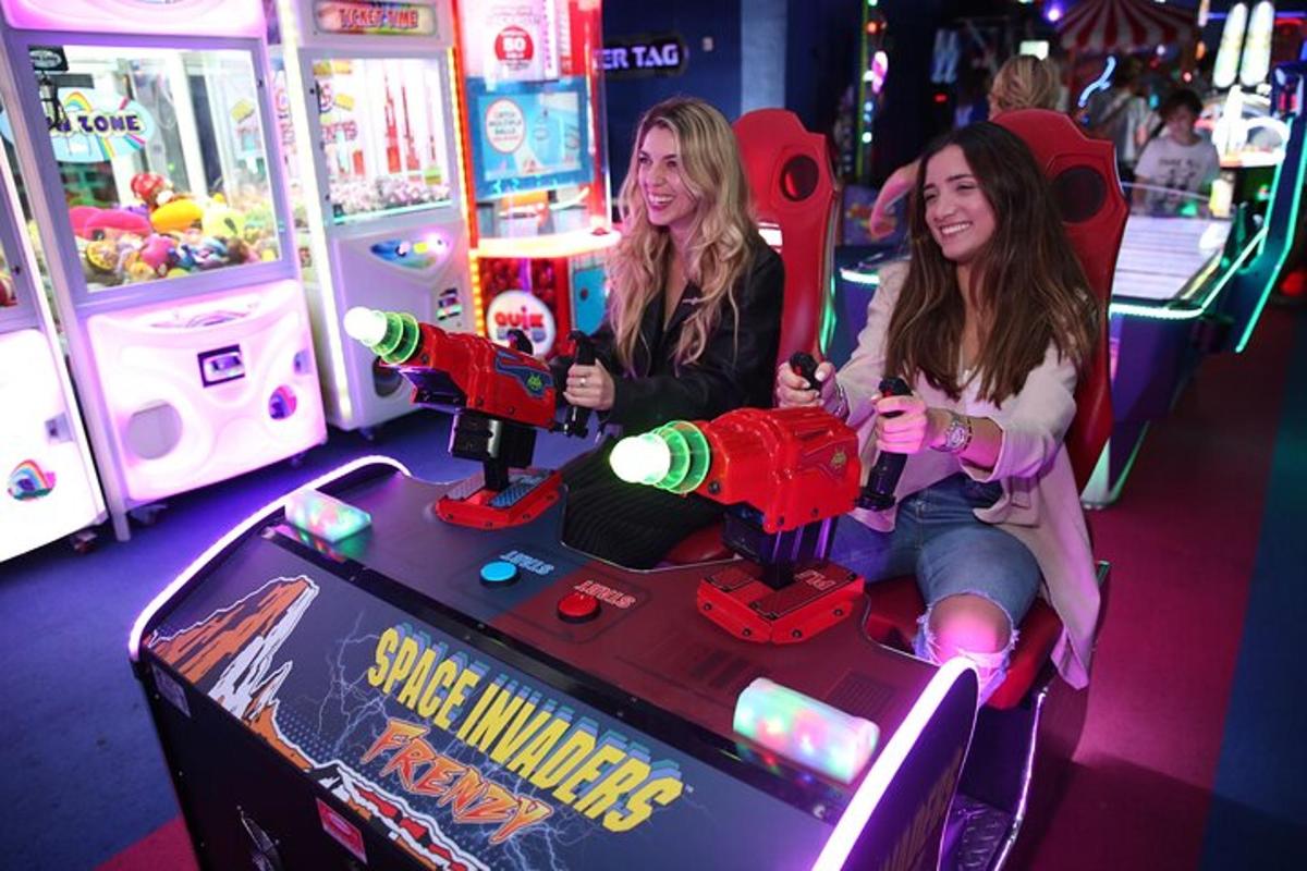 duas meninas jogando videogame em uma máquina de pinball