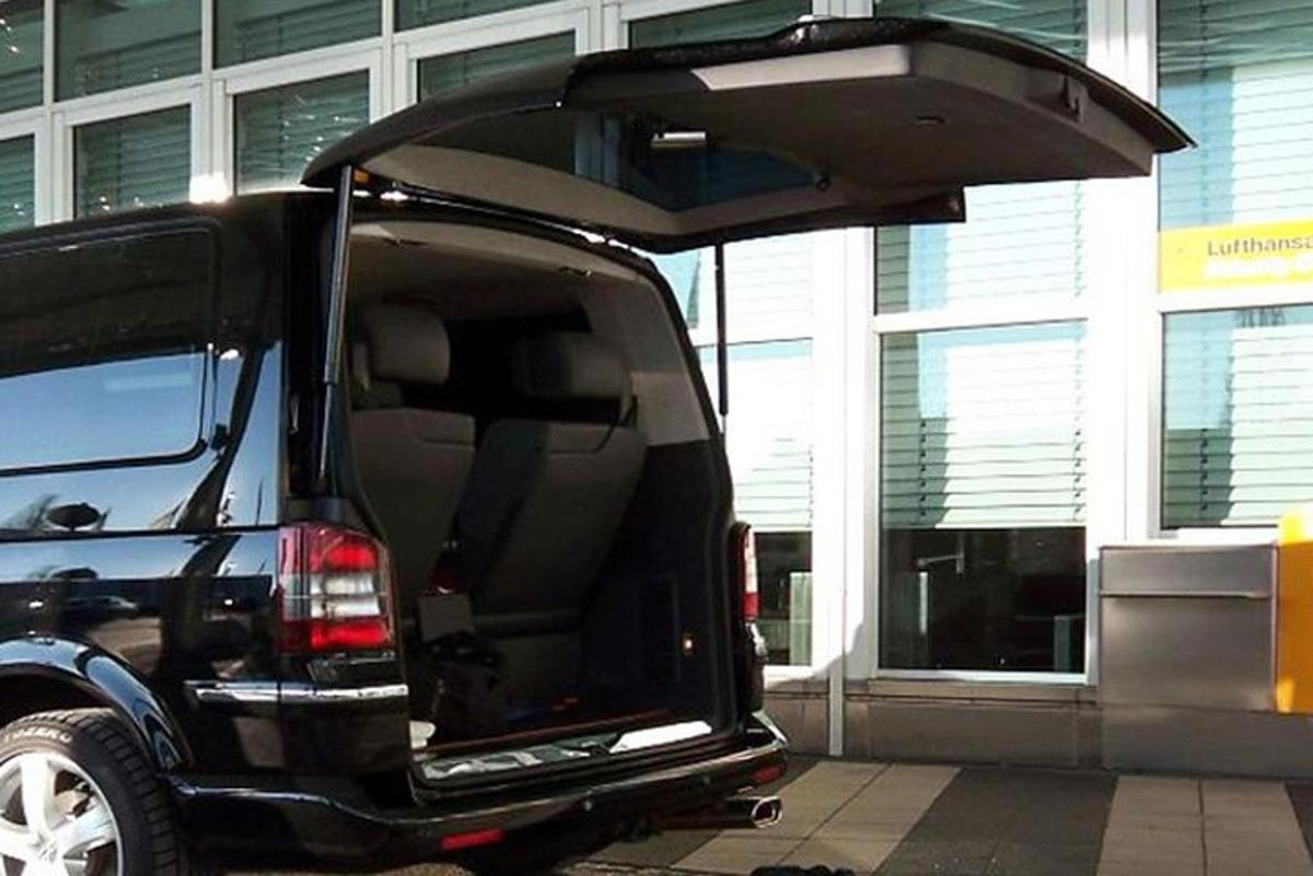 sebuah van hitam dengan pintu terbuka duduk di tempat letak kereta