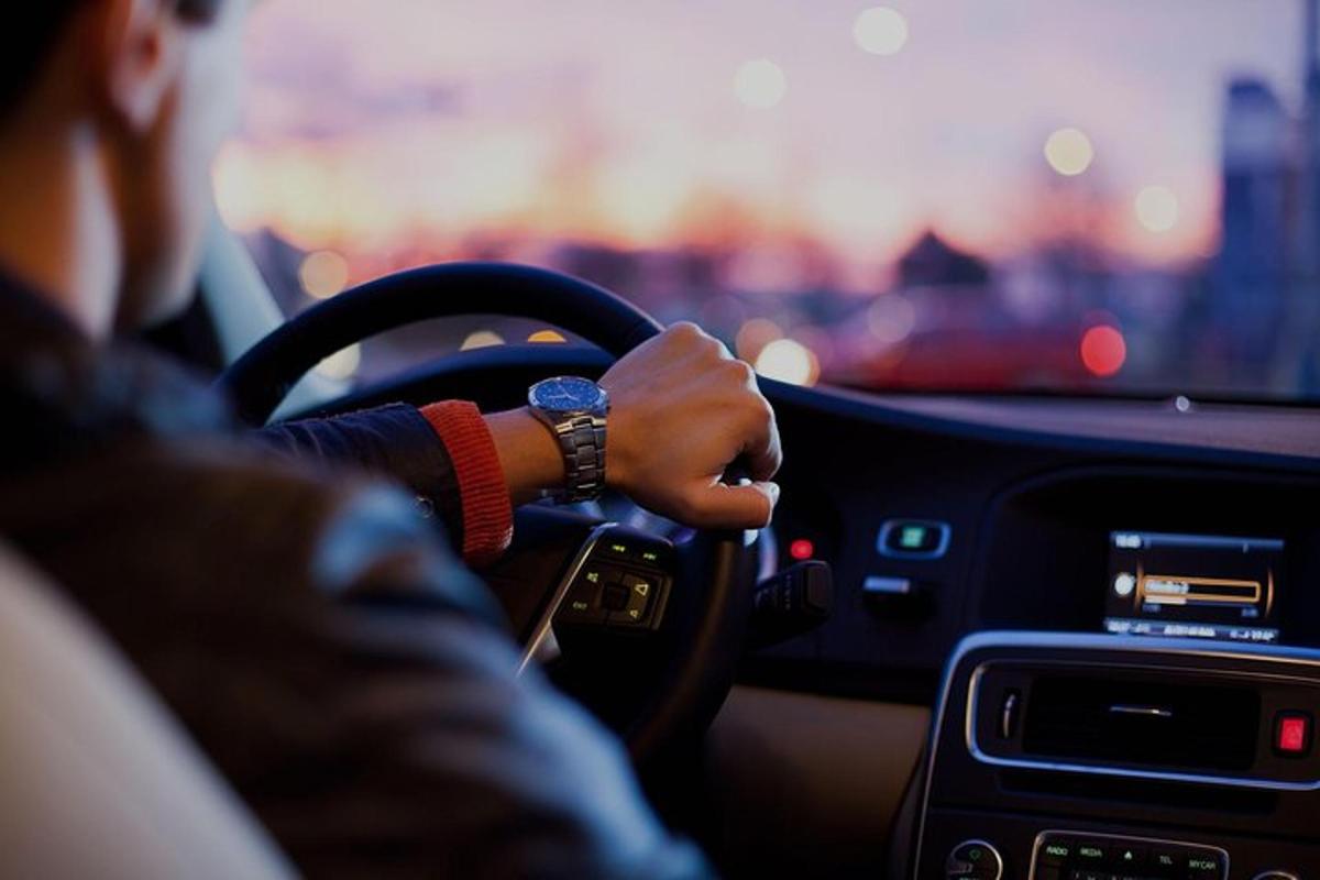a person driving a car with their hand on the steering wheel