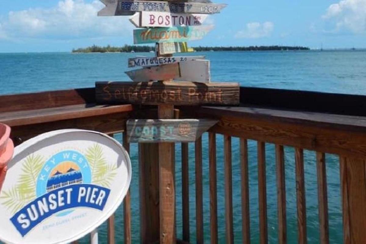 a sign for a sushi pier with the ocean in the background