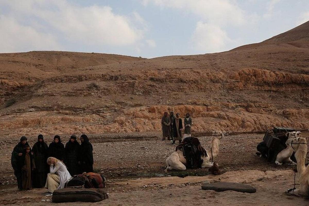 un gruppo di persone in piedi nel deserto con gli animali