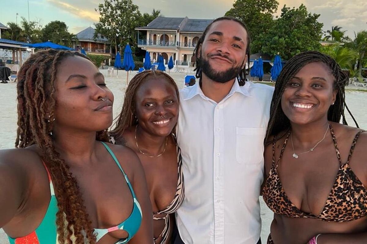 un uomo e tre donne posano per una foto sulla spiaggia