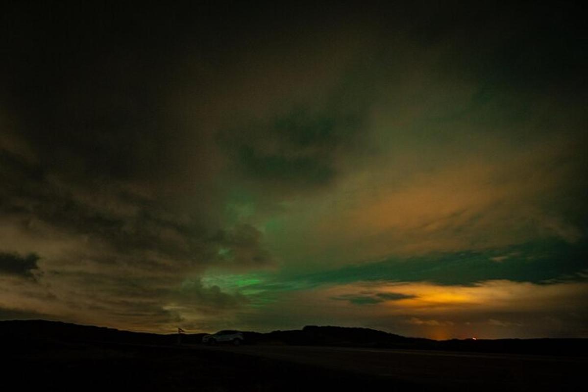 ein bewölkter Himmel mit der Sonne, die über einem Feld untergeht