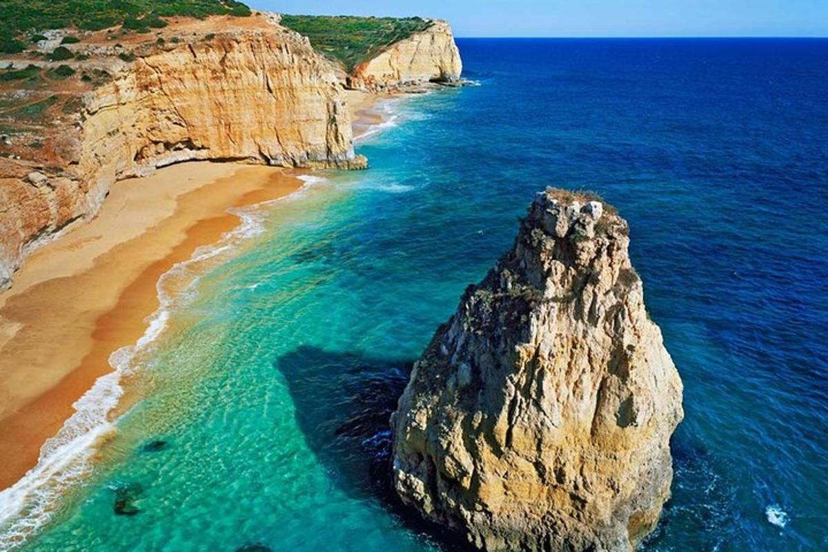 uma grande rocha no oceano ao lado de uma praia