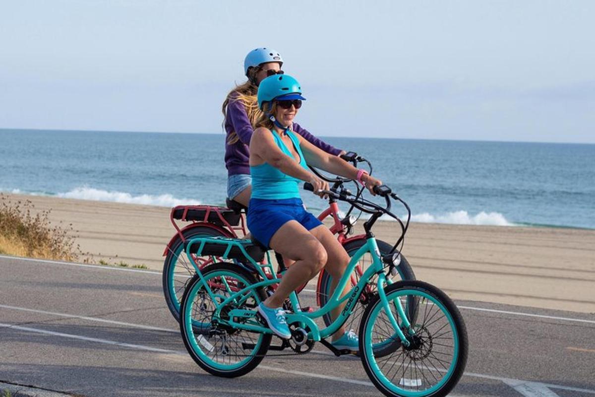 twee mensen fietsen op een weg vlakbij het strand