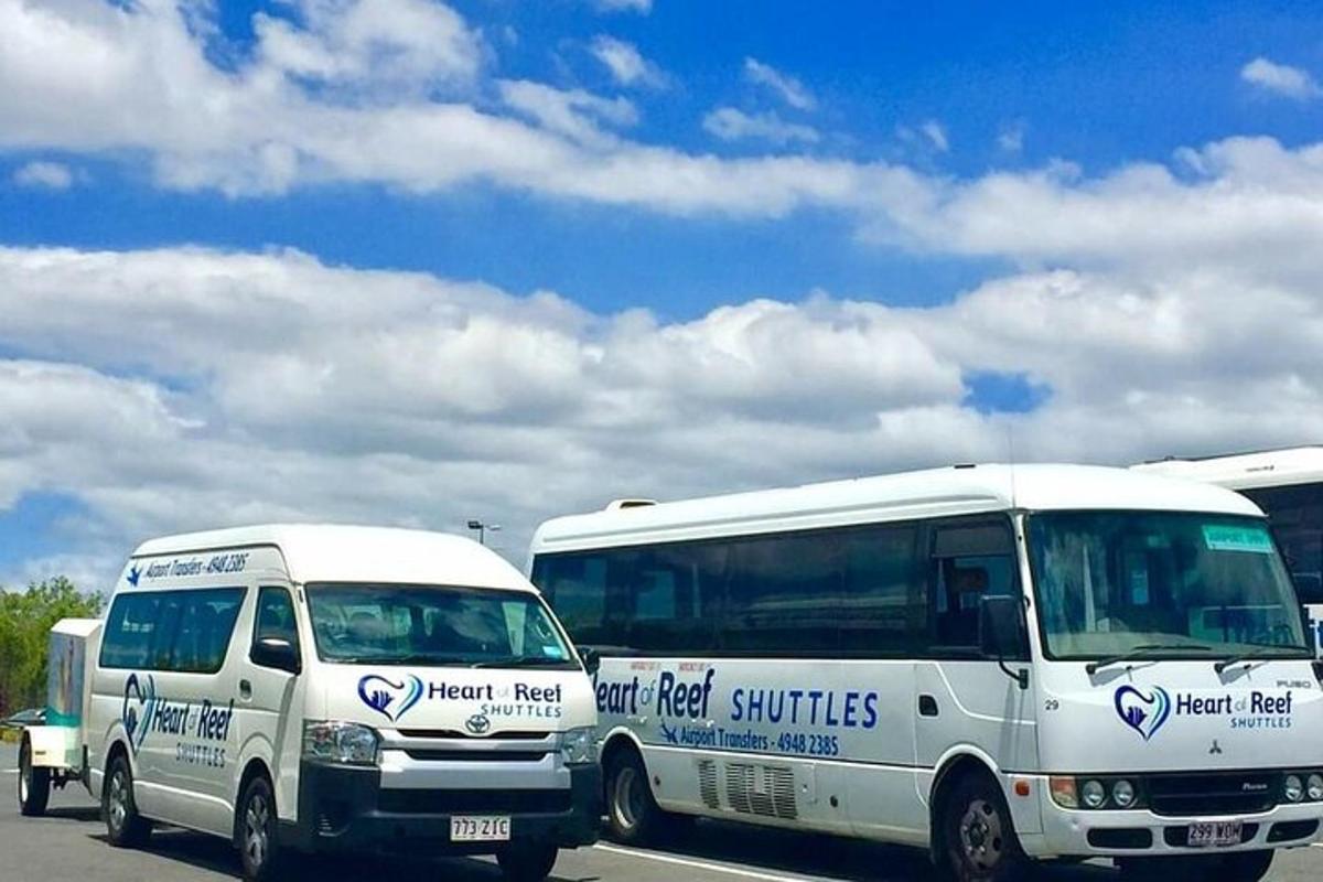 two white vans parked next to a bus