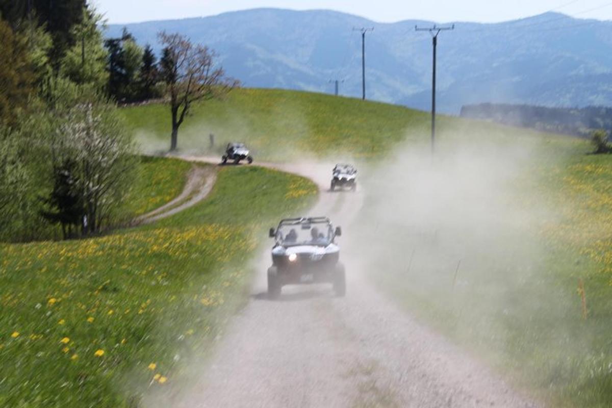 a group of cars driving down a dirt road